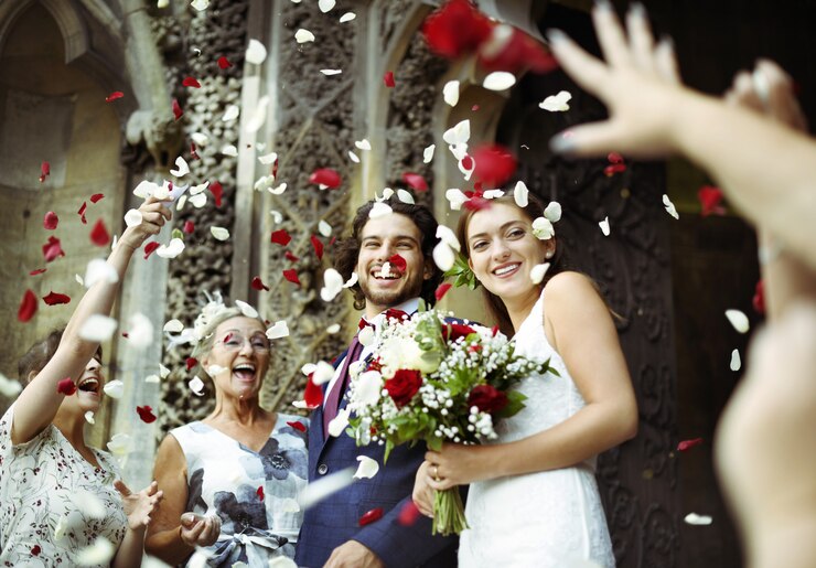 Photo family throwing rose petals at the newly wed bride and groom