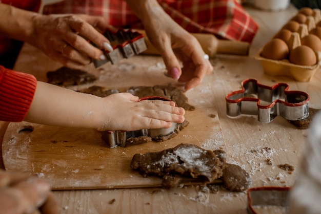 Family time together, xmas holiday preparations. Child's and mother's hands decorating christmas gingerbread with icing on wooden table. Closeup