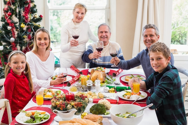 Famiglia che tosta alla macchina fotografica con vino rosso