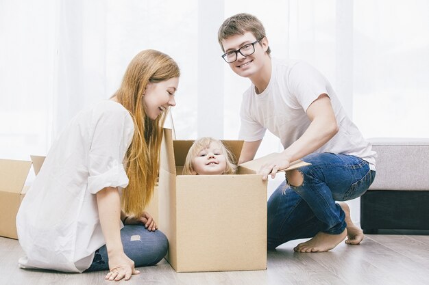 Family together happy young beautiful with a little baby moves with boxes to a new home