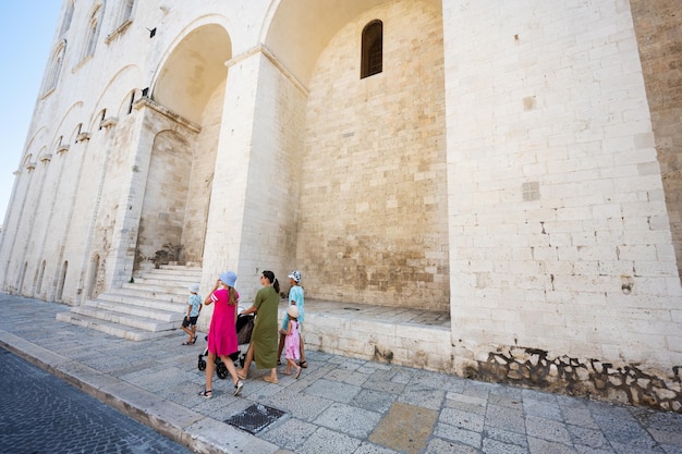 Семья туристов, идущих против базилики Святого Николая в Бари-Пулья, Южная Италия