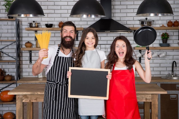 Photo family tradition. happy family in kitchen. pleasant time together. recipe of perfect family dinner. mother and father with little girl holding chalkboard copy space. little girl with parents cooking.