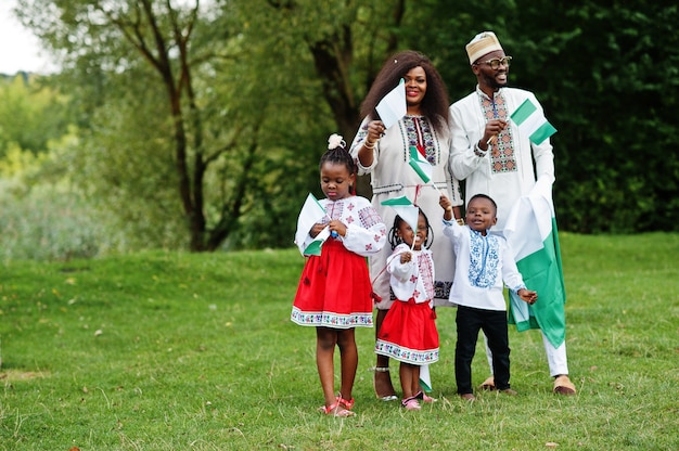 family in traditional clothes with Nigerian flags at park