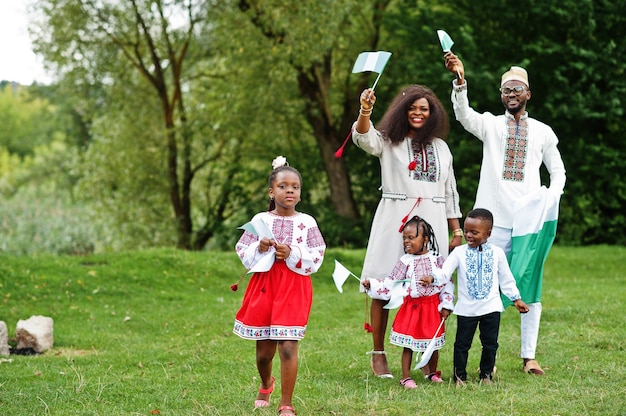 Famiglia in abiti tradizionali con bandiere nigeriane al parco