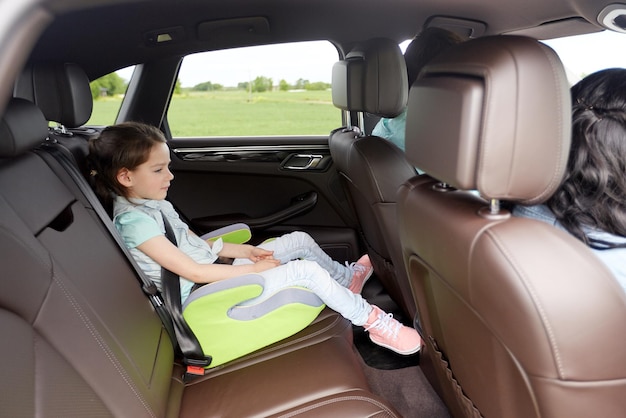 Foto concetto di famiglia, trasporto, viaggio su strada e persone - bambina felice nel seggiolino di sicurezza che guida in auto