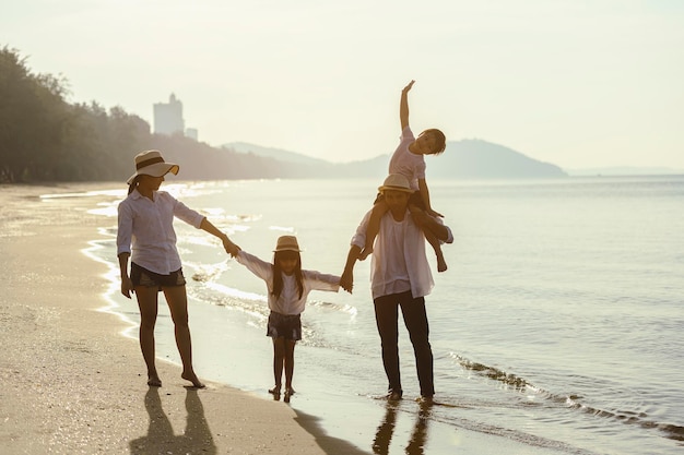 Famiglia, viaggi, spiaggia, relax, stile di vita, concetto di vacanza. famiglia che gode di un picnic. i genitori tengono per mano i loro figli e camminano sulla spiaggia al tramonto in vacanza.
