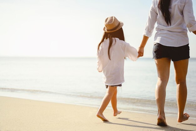 Family, travel, beach, relax, lifestyle, holiday concept. Mother and daughter who enjoy a picnic and sea bathing at the beach on sunset in holiday.