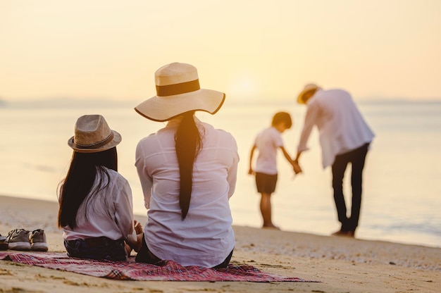 가족, 여행, 해변, 휴식, 라이프 스타일, 휴가 개념. 휴일에 일몰에 해변에서 피크닉을 즐기는 부모와 아이들.