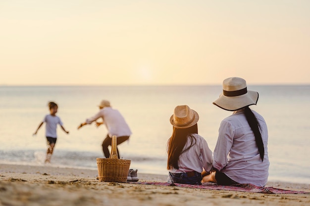 Famiglia, viaggi, spiaggia, relax, stile di vita, concetto di vacanza. genitori e figli che in vacanza si godono un picnic in spiaggia al tramonto.