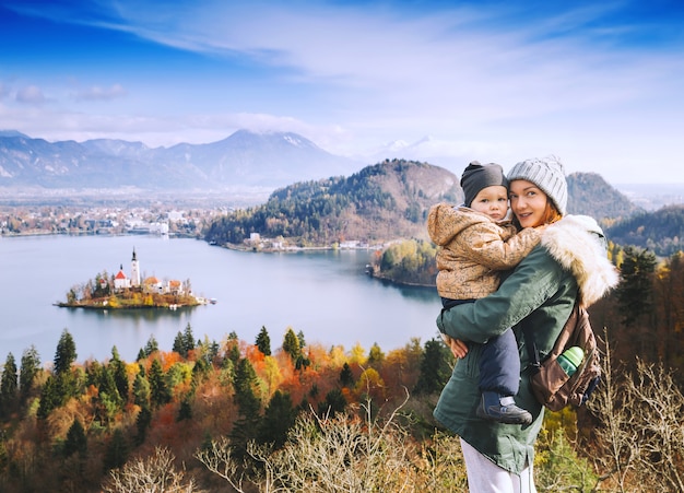 家族旅行ヨーロッパスロベニアヨーロッパのブレッド湖の秋または冬を見ている息子と母