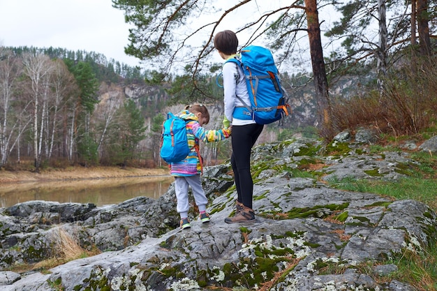 Family travel mother and daughter hiking with backpacks