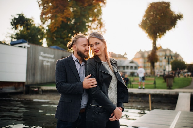 A family of two stands on a pier in Austria's old town at sunset .A man and a woman embrace on the embankment of a small town in Austria.Europe.Felden am Werten see.