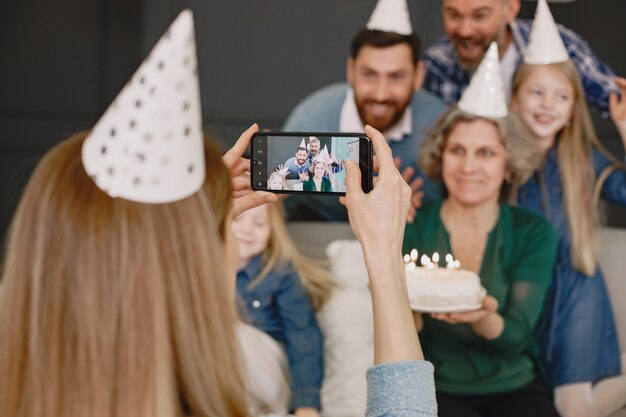 Family and two their daughters celebrate birthdayTwo men and two little girl sitting on a sofa Mother is taking a photo of them