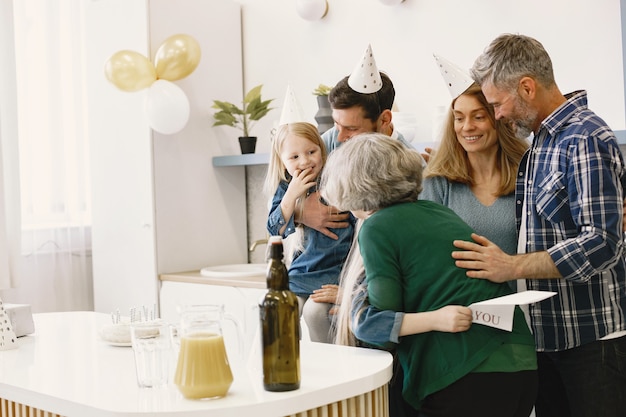 La famiglia e le loro due figlie festeggiano il compleanno della nonna bambina che abbraccia sua nonna