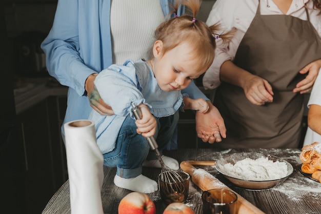 Photo family: two women and children are preparing a birthday cake in the kitchen.