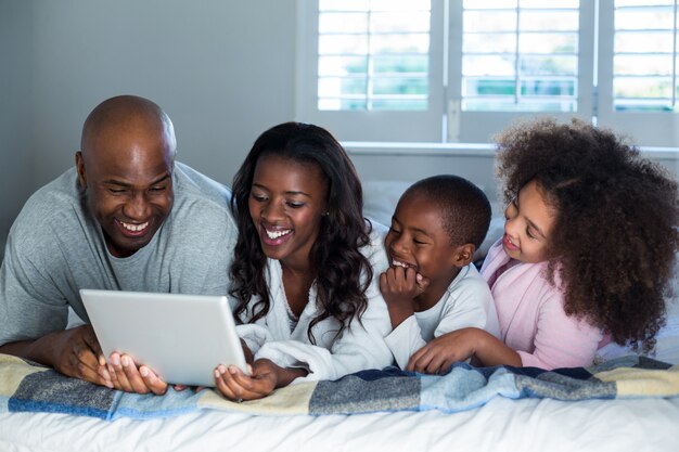 Family using digital tablet on bed