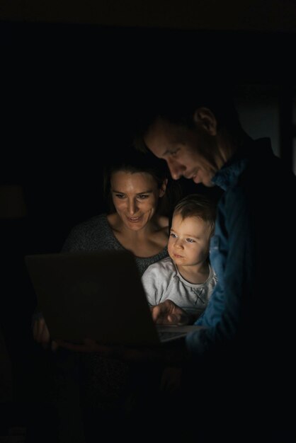 사진 어둠 속에서 노트북을 사용하는 가족