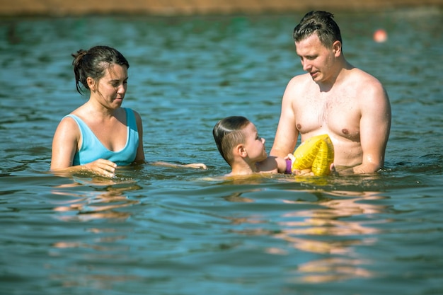 Family vacation concept young mom with dad teaching swimming their son