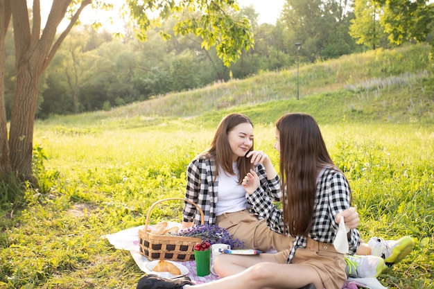 Photo family value two sisters in the park on the grass with copyspace