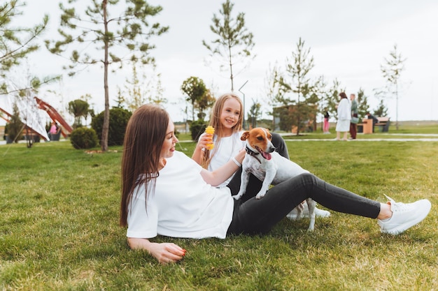 Passeggiata in famiglia nel parco autunnale intrattenimento all'aperto madre e figlia portano a spasso il cane in una calda giornata autunnale soleggiata un bambino gioca con un jack russell terrier nel parco