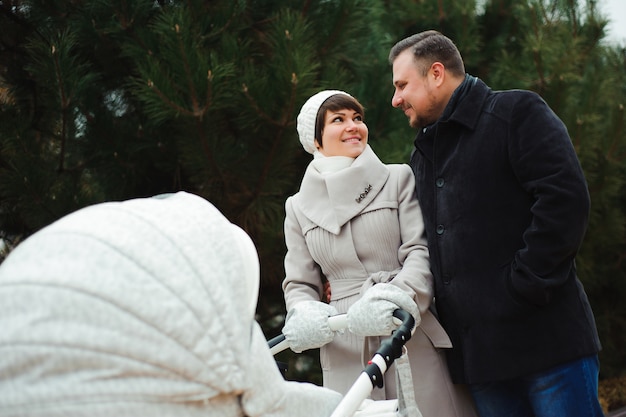 Семейная прогулка в осеннем парке с коляской. Мама, папа и малыш на улице