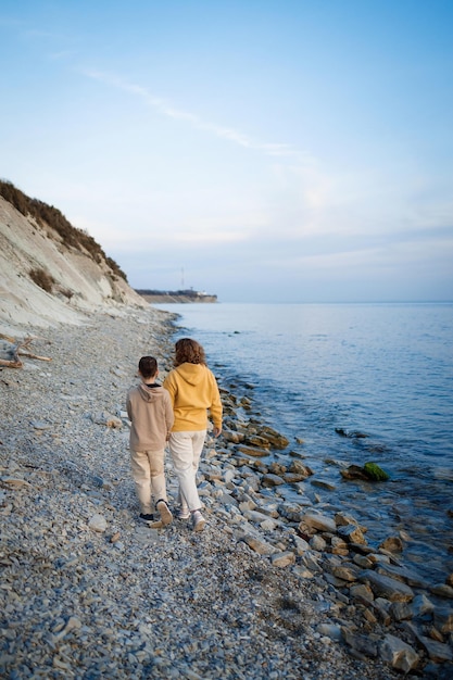 家族は寒い季節に海岸を散歩し、幸せな母と息子が抱き合っている