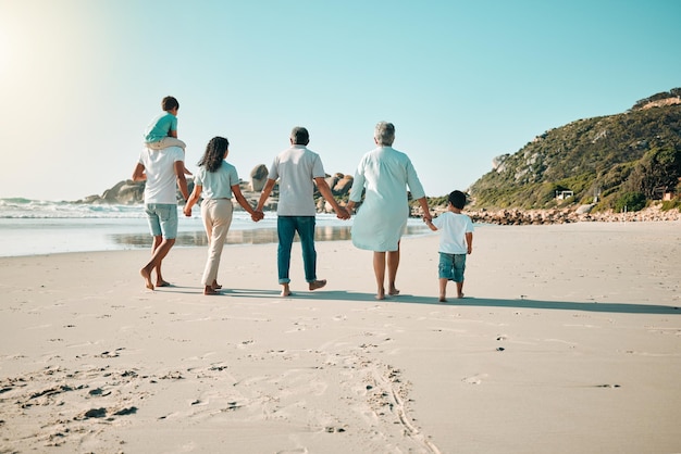 Photo family walking and holding hands outdoor on a beach with children parents and grandparents together men women and boy kids walk at sea with love care and quality time for summer travel vacation