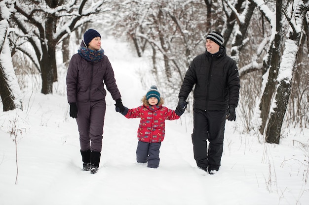 Семья гуляет по заснеженному лесу