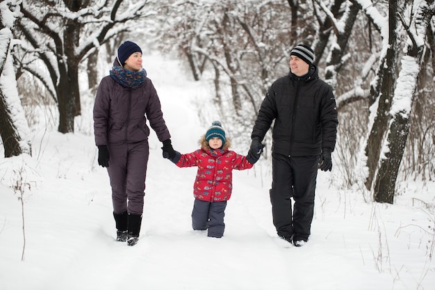 Famiglia che cammina attraverso il bosco innevato