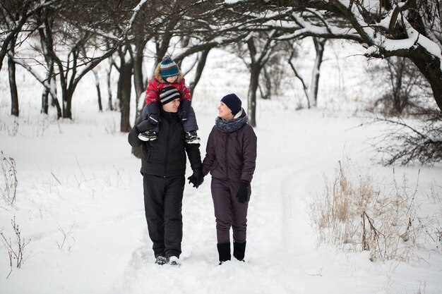 雪に覆われた森の中を歩く家族