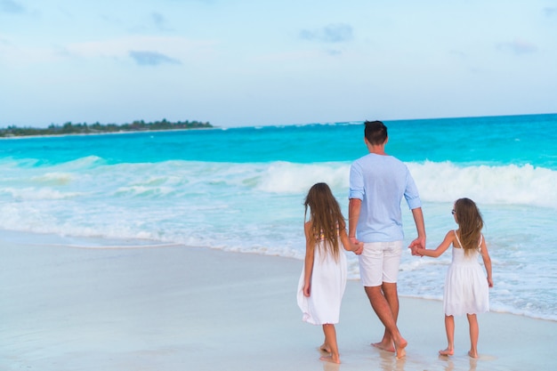 Family walking on white beach on caribbean island in the evening