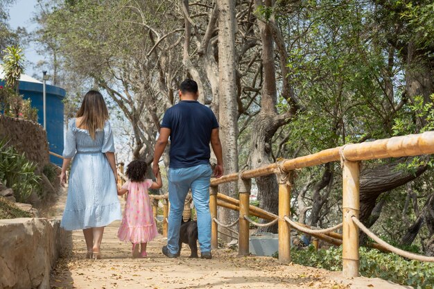 Photo a family walks down a trail with a wooden fence and a little girl holding hands