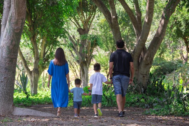 Photo a family walks through a forest with their hands in the air