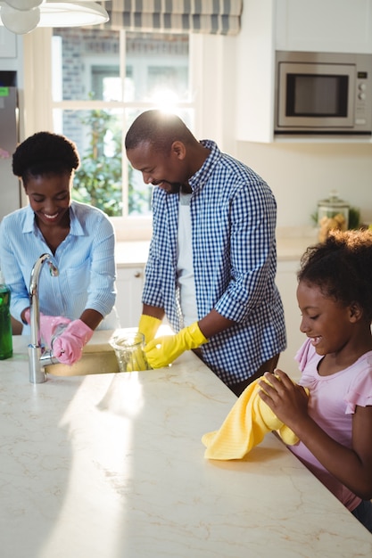 Family washing utensils in kitchen sink