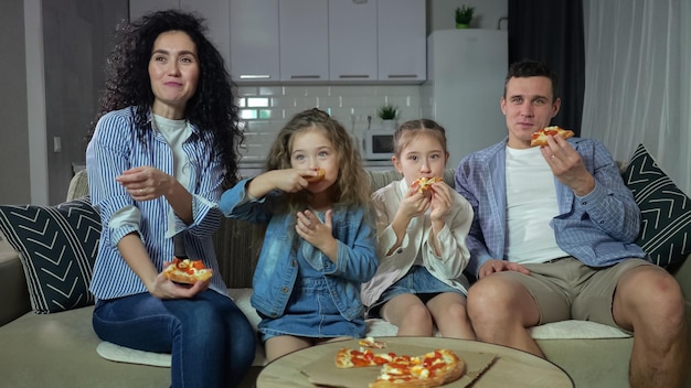 La famiglia guarda la commedia e si diverte a mangiare la pizza a casa