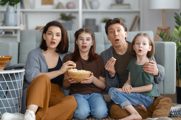 Family watching projector TV movies with popcorn in the evening at home