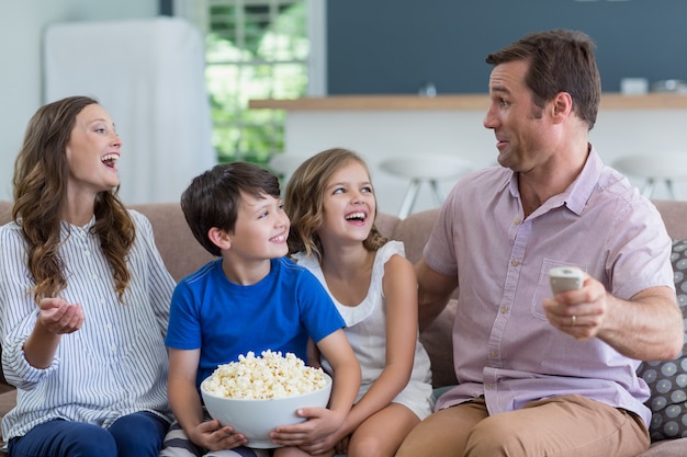 Famiglia che guarda tv e che mangia popcorn in salone a casa