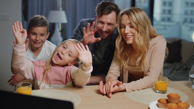 Family waving hands laptop camera at home Parents children making video call