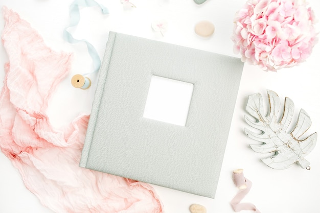 Photo family or wedding photo album with blank space for text, hydrangea flower bouquet, pink blanket, decoration on white surface