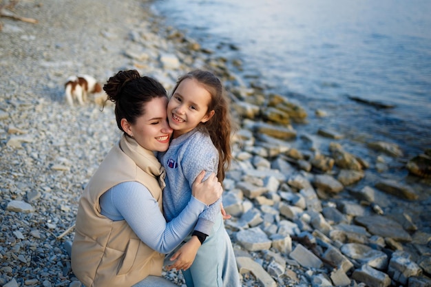 Family weekend by the sea happy mother and daughter have fun on a walk sunset on the sea