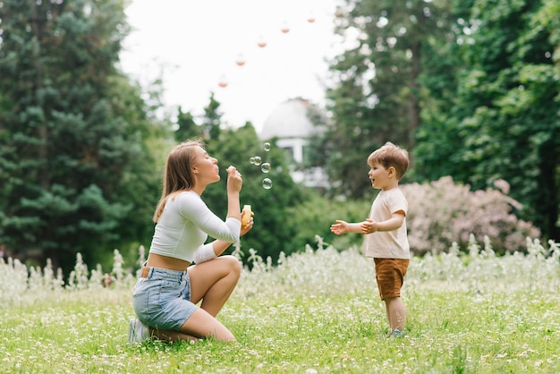 Photo family weekend of a mother and her little son loving parent having fun blowing soap bubbles with a three year old boy