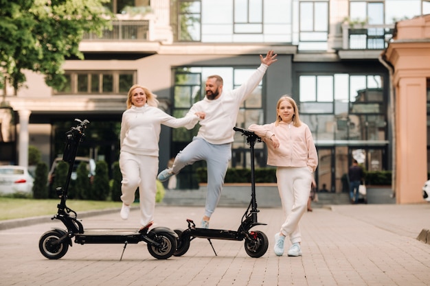 A family in white clothes rides electric scooters in the city.Outdoor activities.