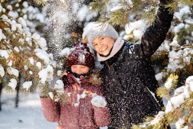 숲에서 가족 겨울 산책 아이 가족 습관 키우기 어머니와 딸은 화창한 서리가 내린 날씨에 숲에서 겨울에 즐거운 시간을 보내고 있습니다 어머니의 포옹
