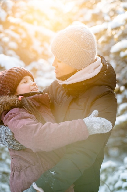 写真 森の中の家族の冬の散歩 子供を育てる 家族の習慣 母と娘は晴れた凍るような天気の森で冬に楽しんでいます 母の抱擁