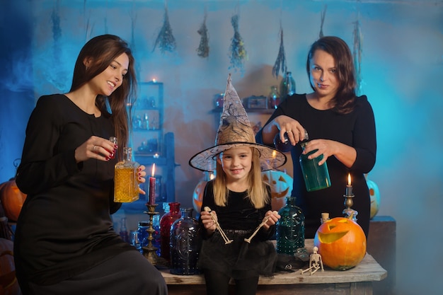 Photo family of witches with potions and halloween pumpkins at home