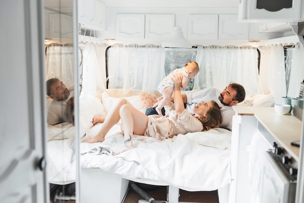 Family with baby on the bed in trailer in the morning