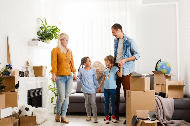 Family with cardboard boxes standing in row at home