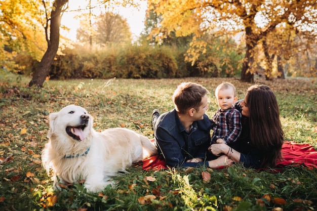 Photo family with a child and a golden retriever in an autumn park