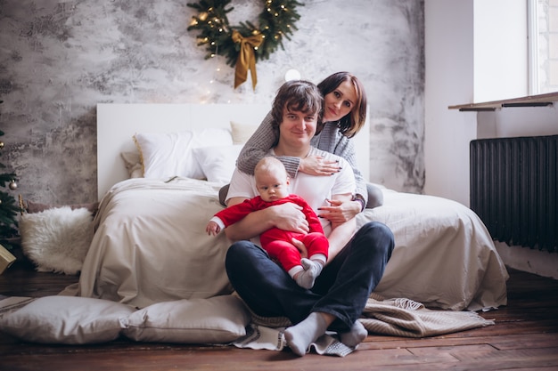 Family with child at home on bed near Christmas tree