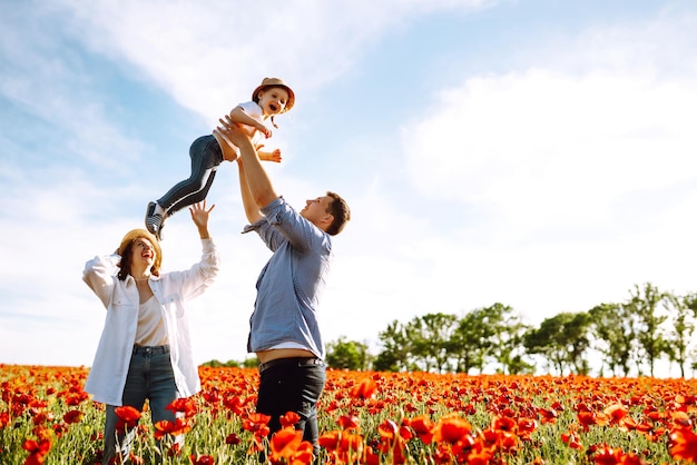 Family with a child walking on a poppy field Mother father little daughter having fun on poppy field